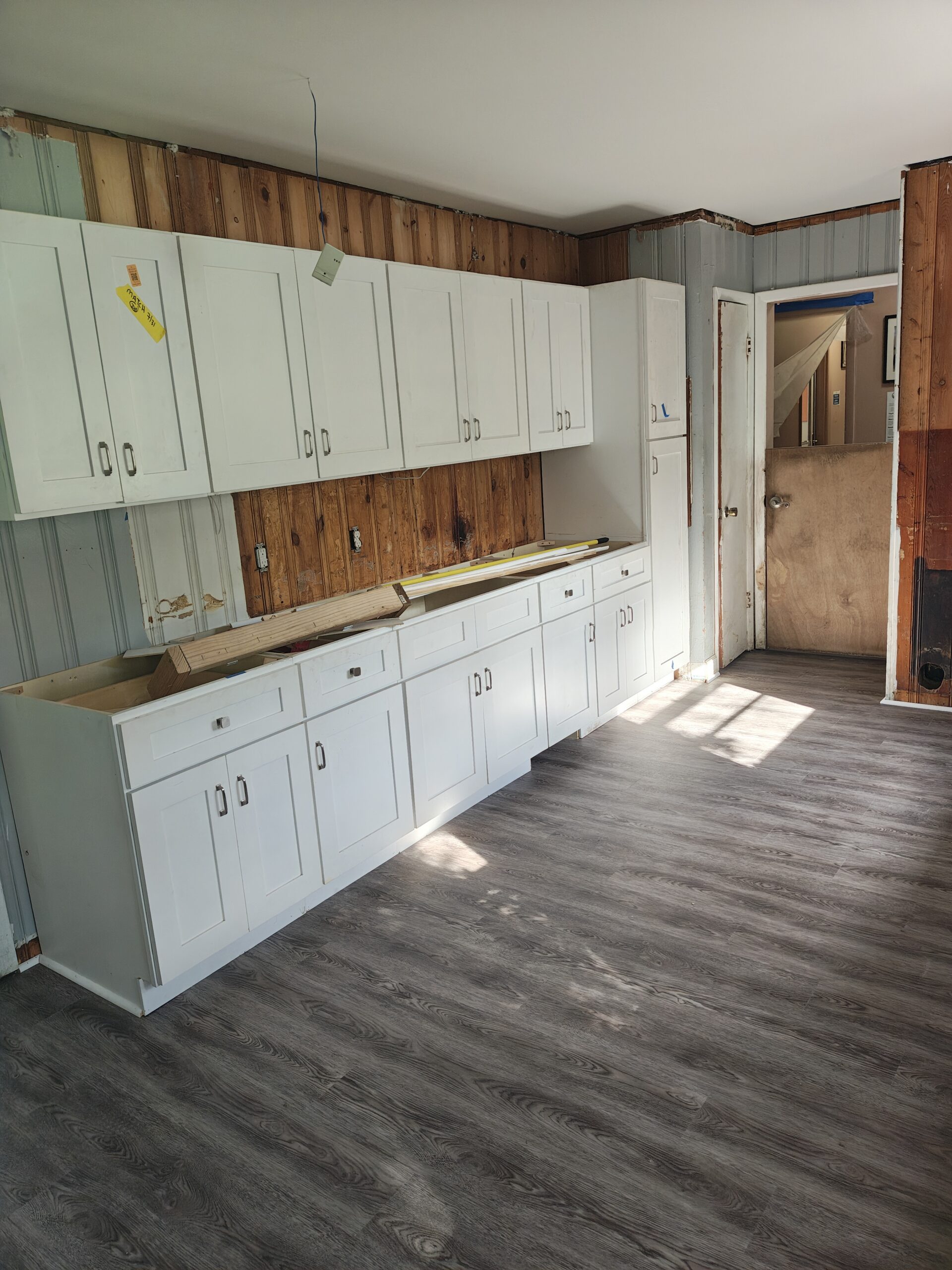 New white cabinets and a wood counter installed along the wall of the PAWS Atlanta Cat Cottage, with new flooring down.
