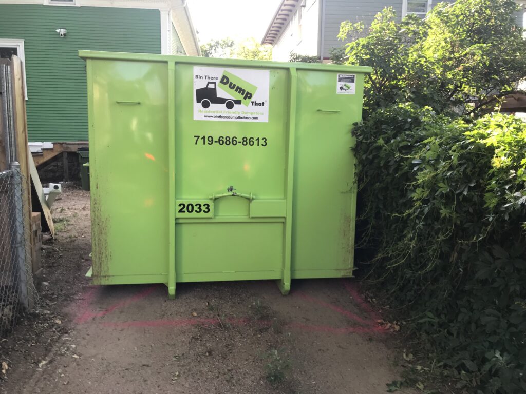 Dumpster placed in a tight backyard with placement paint marked on the ground
