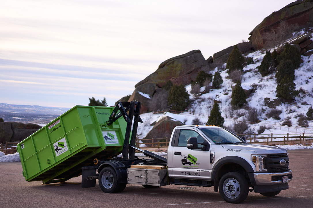 Green roll off dumpster truck placing a bin in the Colorado foothills