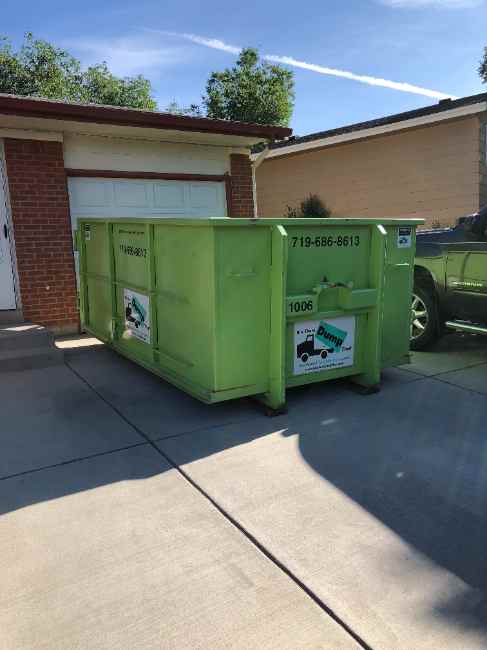 Dumpster positioned on a driveway right beside the garage door