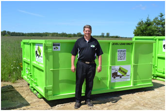 Mark Crossett, founder of Bin There Dump That, standing in front of 12 yard bin