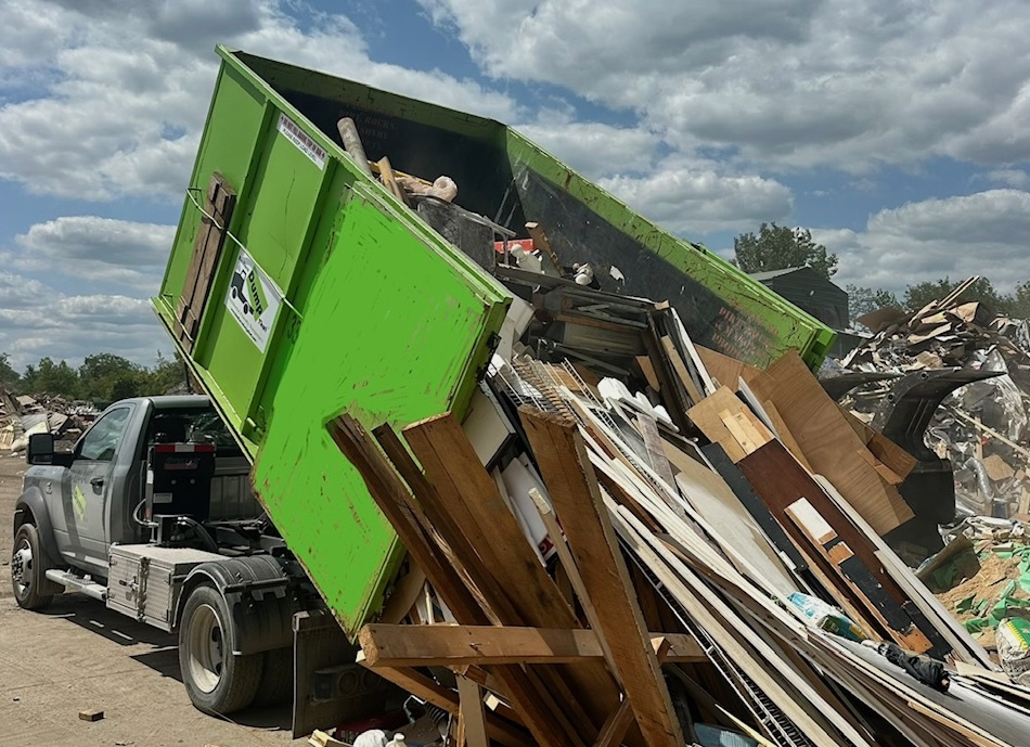 Bin There Dump That truck unloading a full dumpster of construction debris at a transfer station near Plainfield, IL