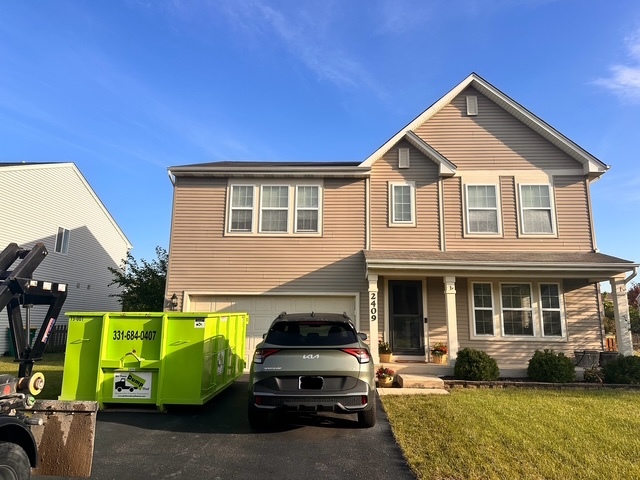 Green Bin There Dump That dumpster rental being delivered to a residential driveway in Plainfield, IL.