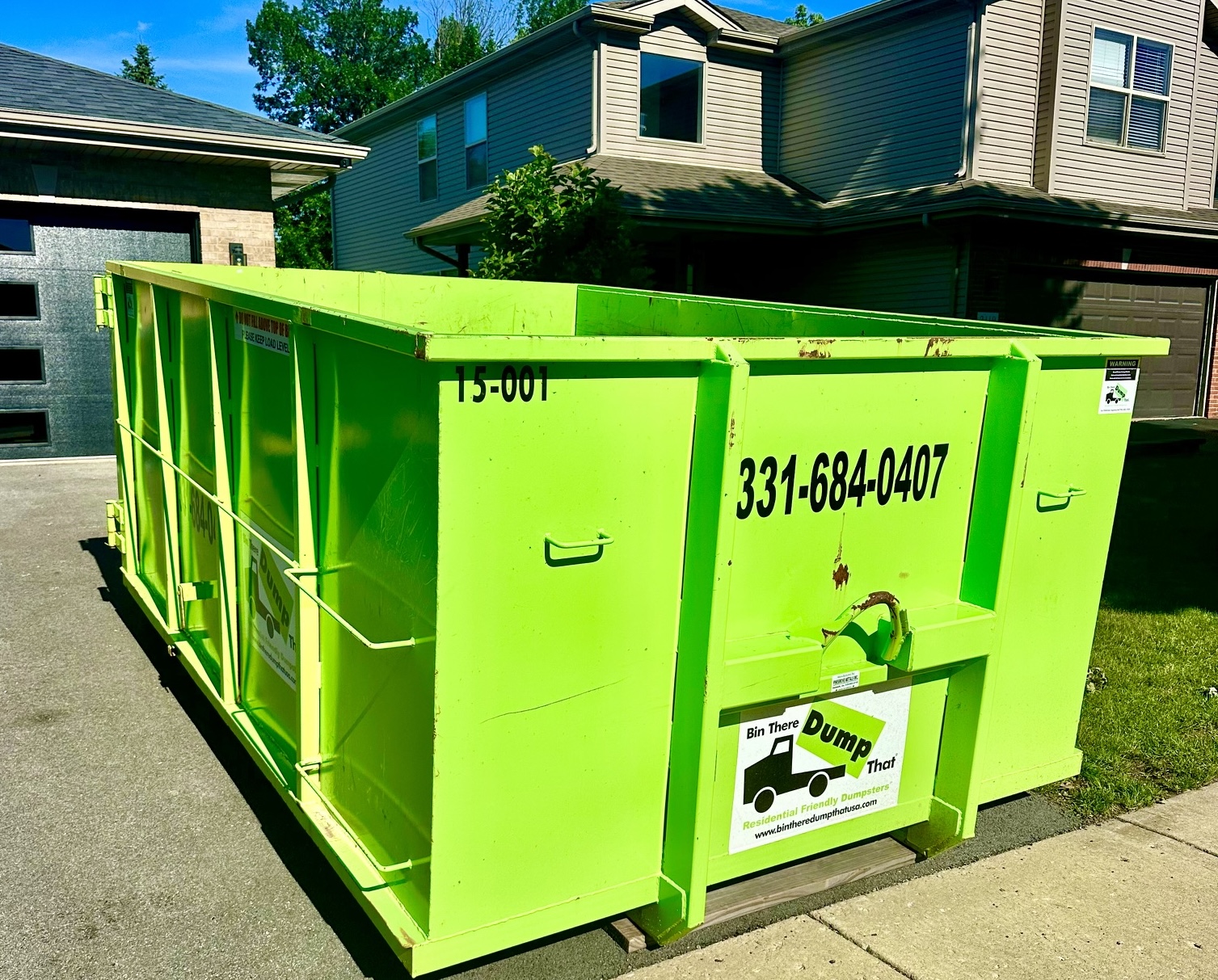 Dumpster placed in a driveway with the sidewalk left clear for pedestrians